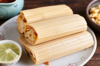 Steaming jackfruit tamales on a plate with salsa, lime wedges, and fresh cilantro